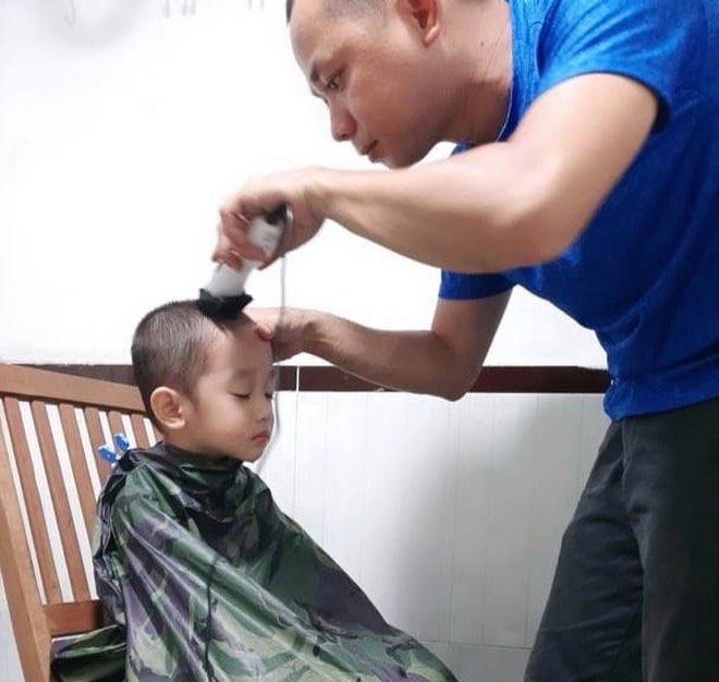 Sau khi cắt tóc cho mình (với sự hỗ trợ của vợ), anh Tiến Minh “ủi” cho các con /// Ảnh: NVCC